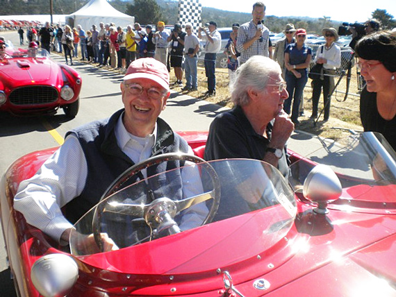 Pebble Beach historian and author Bob Devlin (red hat) smiles for the camera while Pebble Beach Concours d’Elegance Chief Judge Emeritus, Ed Gilbertson, chats with Kandace Hawkinson. Devlin and Gilbertson are ready to tour the old course in Phil Bachman’s 166 Vignale Spyder. Derek Hill handles the microphone directly behind Gilbertson. Credit: Carol Seielstad